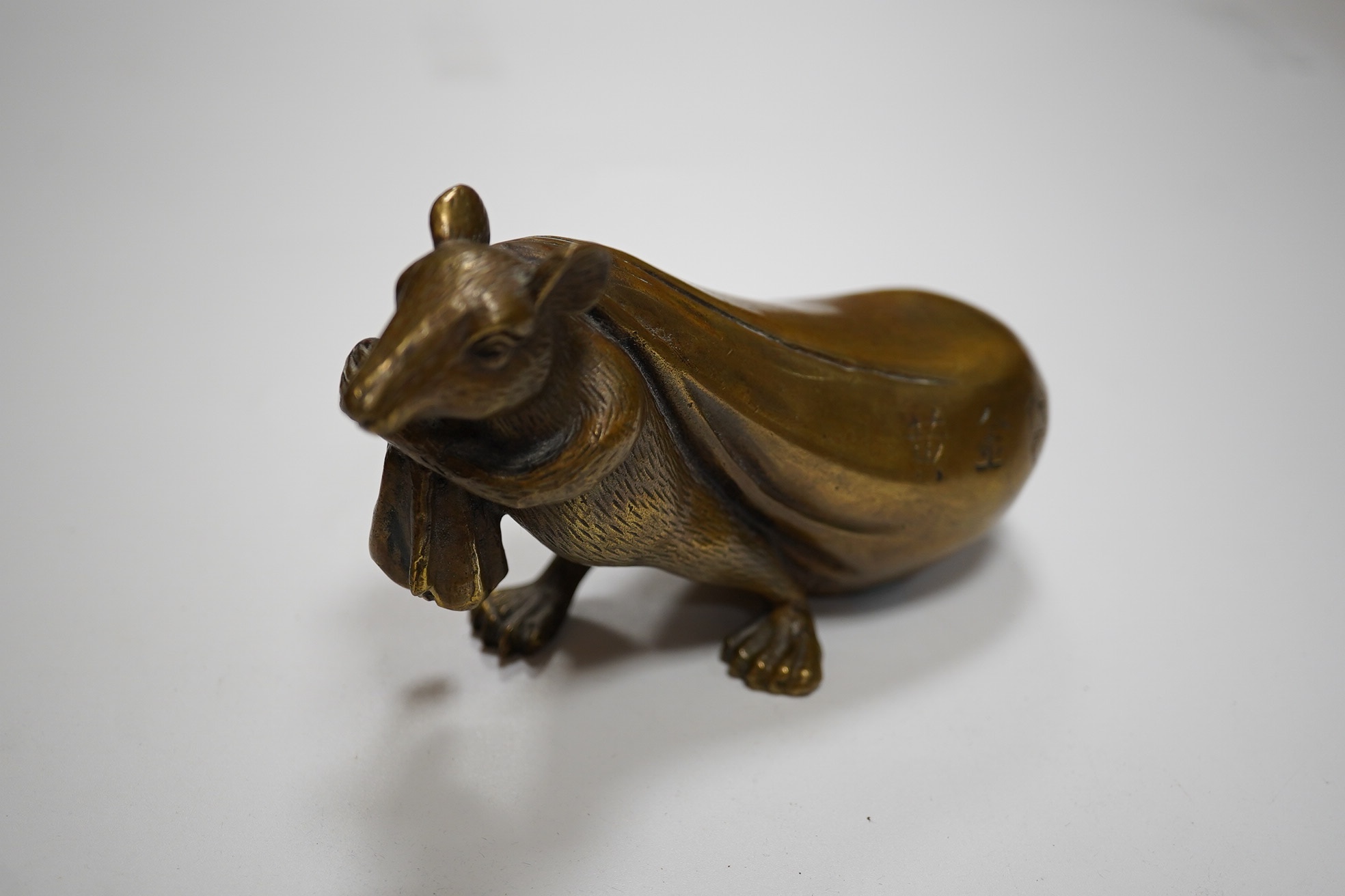 A Chinese bronze rat carrying a sack, signed in casting, 14cm long. Condition - fair